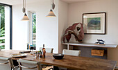 Pendelleuchten über einem hölzernen Esstisch mit Tierskulpturen in einem Haus in Essex UK