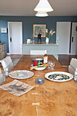 Pendants above wooden dining table with plates and salad in open plan Essex home UK