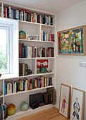 Framed art and bookshelf at window in Essex bedroom UK