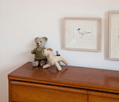 Soft toys on wooden sideboard with framed picture of bird in Essex home UK
