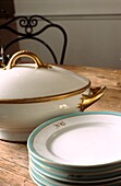 French gold rimmed porcelain dinner service on French provincial pine dining table