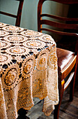 Detail of crocheted lace tablecloth with dining chairs