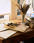 Brushes sketchbooks and quill feathers on a wooden desk in the bedroom