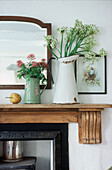 Detail of Mantelpiece in living room with display of cut flowers in vases