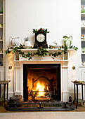 Open fire burning in grate with festive decorations on the mantlepiece