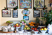 Tiled sideboard filled with festive fruit with a background of pictures decorated with holly
