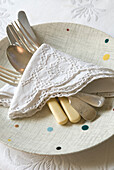 Detail of vintage plate cutlery and lace napkin on a table