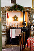 Brennende Kerzen mit goldenem Stern über Weihnachtsmannfiguren hinter einem schwarzen Küchenherd in einer Landhausküche