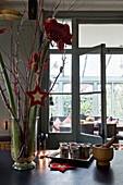 Christmas flowers and star-shaped decorations on worktop with silver goblets and view to dining room extension