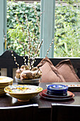 Plates and Christmas bulbs with catkins on dining table at window