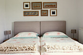 Twin beds with headboards under artwork of birds 