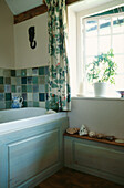 Vine trellis fabric in bathroom with shell and stone decorated shelves and green ceramic tiles