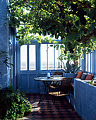 Blau gestrichener, sonnenbeschienener Wintergarten mit Weinrebe