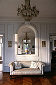 Upholstered sofa below window in French apartment reception hallway
