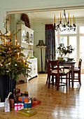 Christmas tree and presents in the open plan dining room with chandelier and table set for christmas
