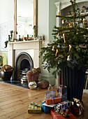 Christmas tree and presents in living room with fireplace in background