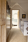 Banister cut from panels of MDF with coir matting and view along corridor through open door to bathroom 