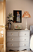 Chest of drawers with objects under artwork in bedroom