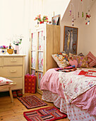 Gingham covered bed with painted chest of drawers and wardrobe in untreated wood 