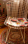 Metalwork chair with 1950s retro print fabric cushion on rag rug