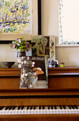 Music book and vase of flowers on wooden piano