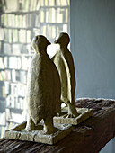 Two penguin sculptures on wooden shelf