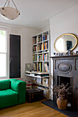 Green sofa in living room with built in bookcase and fireplace