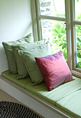 One pink and three green cushions on mill conversion window seat