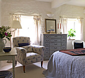 Floral gemusterter Sessel in einem Schlafzimmer im Landhausstil mit niedriger Decke