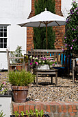 Exterior of period property with terracotta pots wooden garden furniture and gravel
