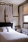 Bedroom with white bed linen and vintage lace canopy