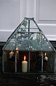 Glass lantern with burning candles and flowers inside