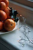 Christmas decoration with pile of oranges and holly leaf