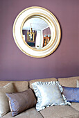 Sofa mit Kissen und rundem Spiegel