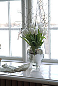 White tulips in glass vase on window still
