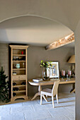 Bookcase and light wood table in farmhouse kitchen with arched ceiling Wiltshire