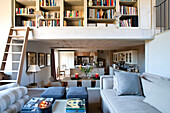 Elevated bookcase above kitchen and living room in barn conversion Wiltshire