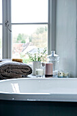 Scented candles and folded towel on windowsill beside bathtub