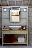 Wash stand on wooden panelled unit set against exposed stone