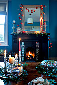 Lit candles and fairy lights with open fire at Christmas