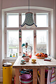 Patterned lampshade hangs above wooden table in Odense kitchen