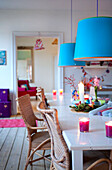 Blue pendant shades hang above Odense dining table with cane chairs
