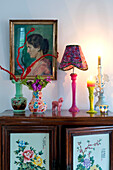 Beleuchtete Kerze und Vasen mit Kunstwerken auf einem Beistellschrank in Odense