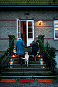 Mother and daughter climb steps with lit lanterns in winter
