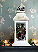 Lit candles and pinecones in lantern on mantlepiece London