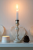 Beleuchtete Kerze und Tannenzapfen auf einem Regal in einem Londoner Haus