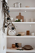 Star shapes hang in twig arrangement with homeware on shelves