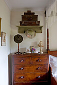 Suitcases and vintage hats with tea tray on wooden chest of drawers in Devon bedroom