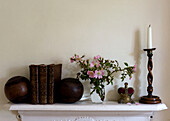 Schnittblumen mit Büchern und Kerzenleuchter auf dem Kaminsims in einem Haus in Devon