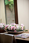 Pink flowers in metal tray reflected in mirror